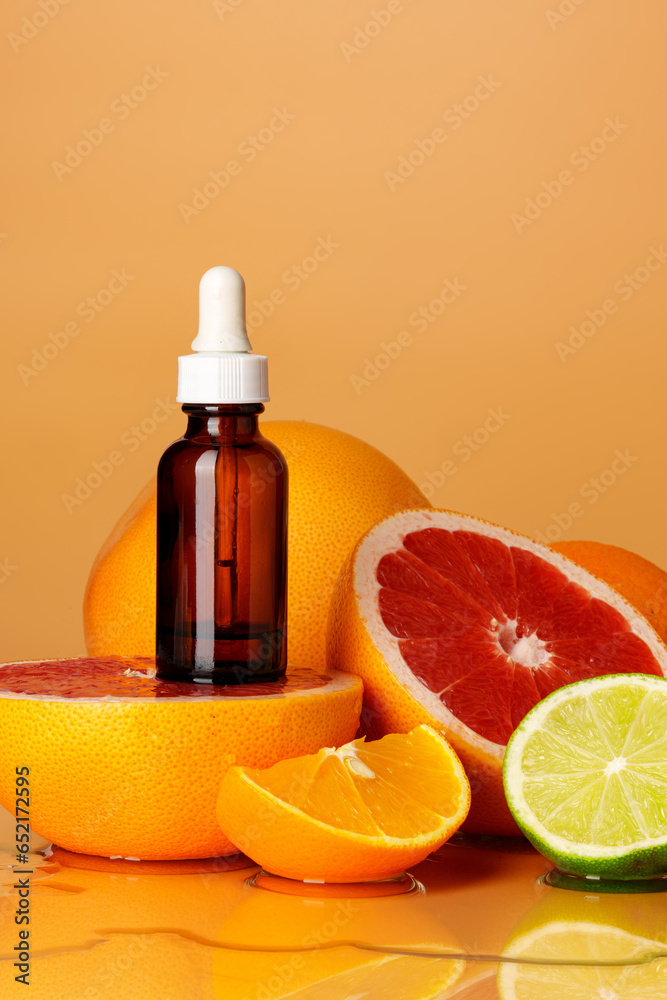 Glass bottle with essential citrus oil on orange background Glass bottle with essential citrus oil on orange background
