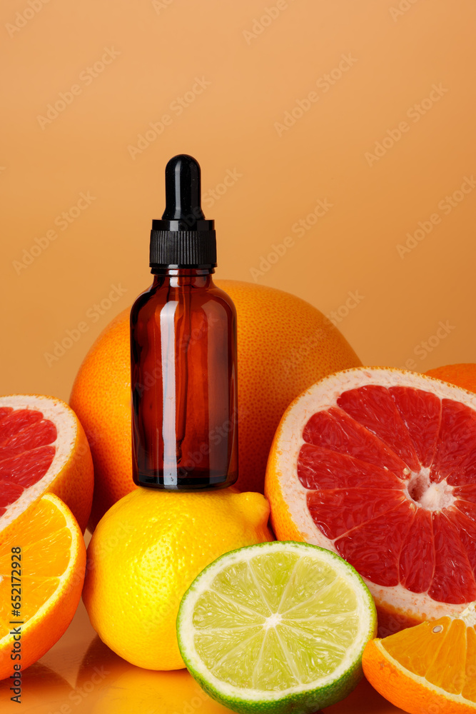 Glass bottle with essential citrus oil on orange background Glass bottle with essential citrus oil on orange background