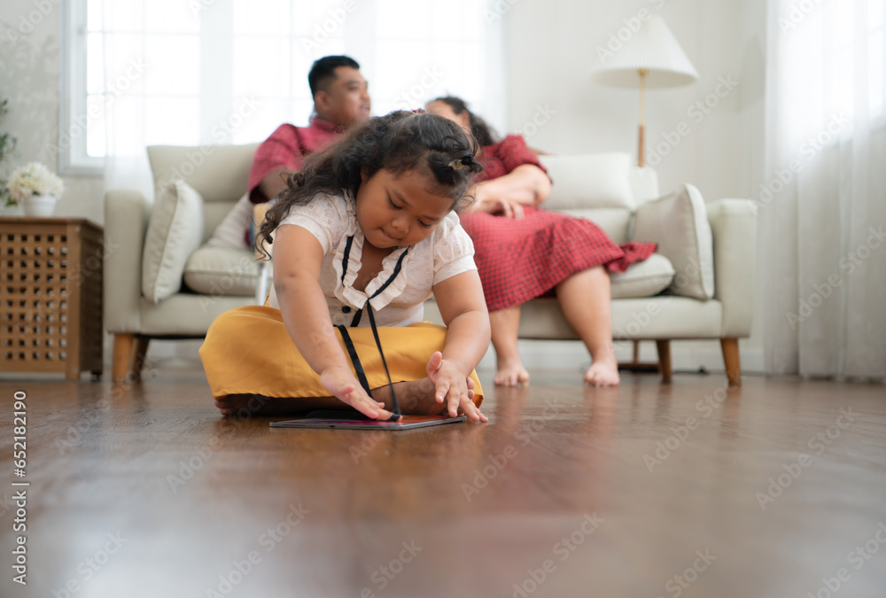 A plus size family with a father wearing a prosthetic leg, During rest time allow daughter to play games on tablet in the living room of the house. A plus size family with a father wearing a prosthetic leg, During rest time allow daughter to play games on tablet in the living room of the house.