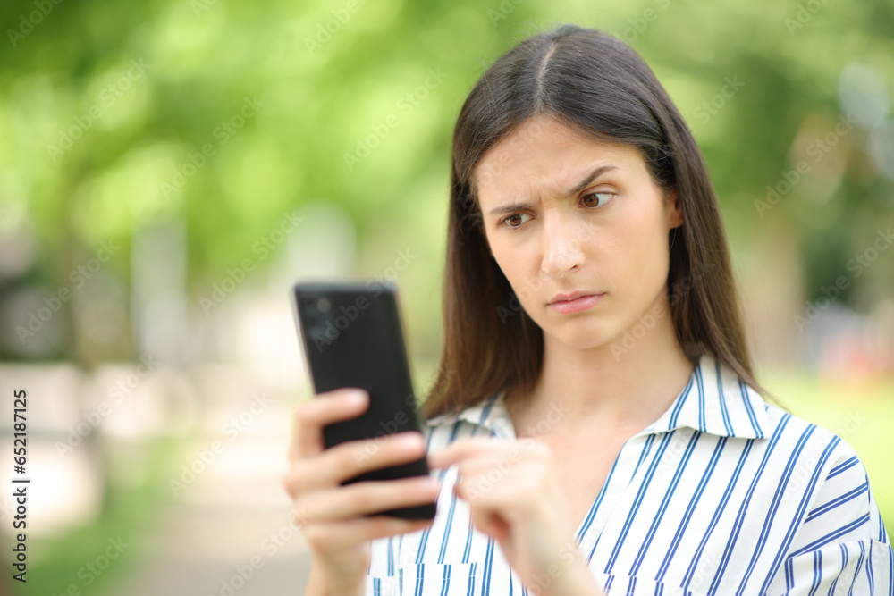 Woman reading suspicious message on phone - obrazy, fototapety, plakaty 