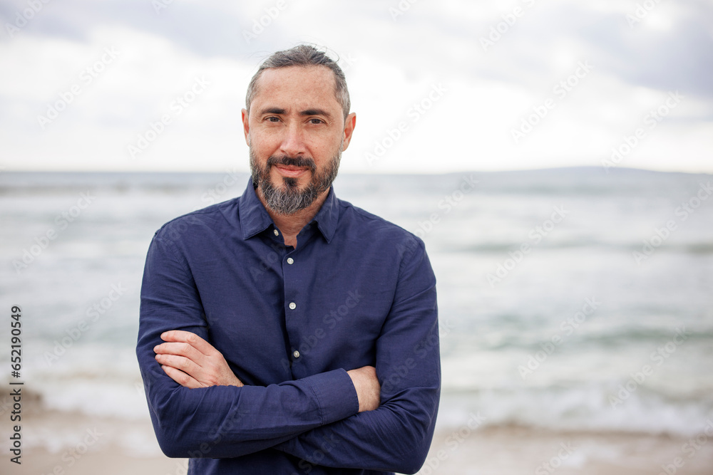 Mature man with arms crossed standing at beach