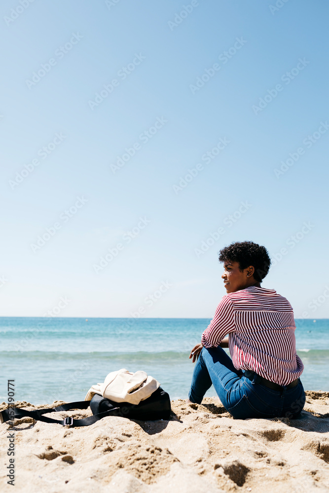 Woman sitting on the beach, enjoying the sun after work Woman sitting on the beach, enjoying the sun after work