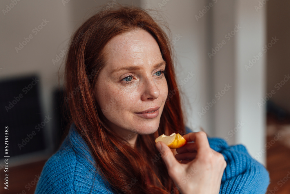 Thoughtful woman eating slice of apple at home Thoughtful woman eating slice of apple at home