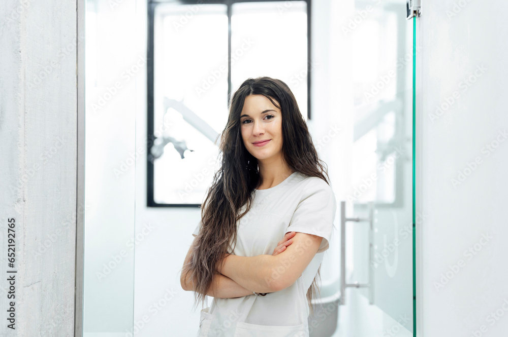 Smiling young dentist standing with arms crossed in dental clinic Smiling young dentist standing with arms crossed in dental clinic