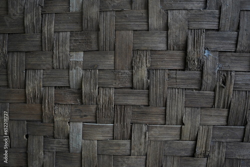 the texture of the woven old bamboo wall with a worn brown color that is worn with age