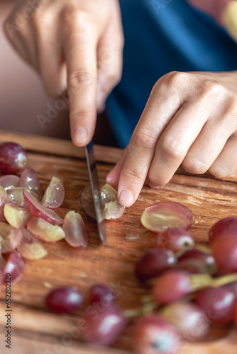 A woman cuts grapes on a cutting board.