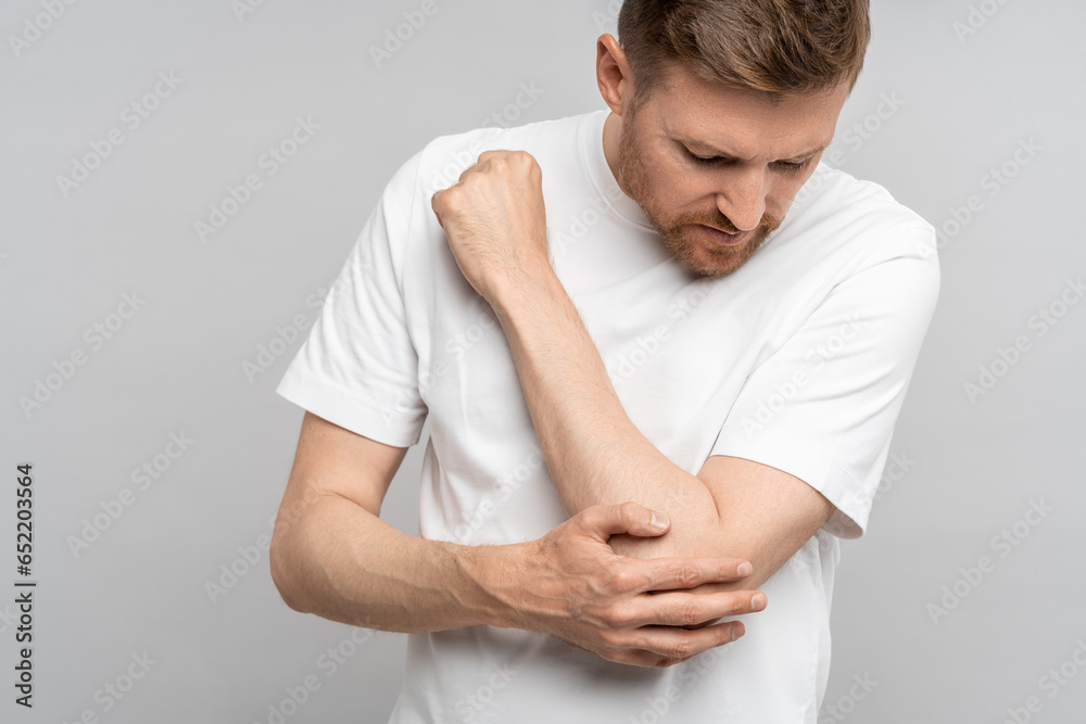 Man touching hand elbow feeling pain isolated on gray background after