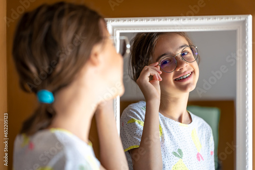 Tableau sur toile A teenage girl looks at herself in the mirror in the morning.