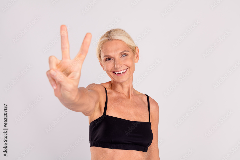 Portrait of stunning satisfied lady toothy smile hand fingers demonstrate v-sign isolated on grey color background Portrait of stunning satisfied lady toothy smile hand fingers demonstrate v-sign isolated on grey color background