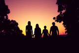 silhouette of a family including father, mother and two children all holding hands against