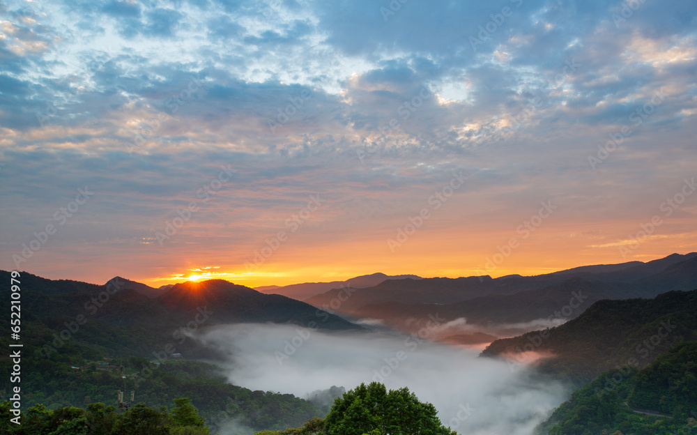 The sun rose at the top of the mountain as the orange-red clouds turned grey. Early morning view of tea gardens, sea of ​​clouds and sunrise, Nanshan Temple.