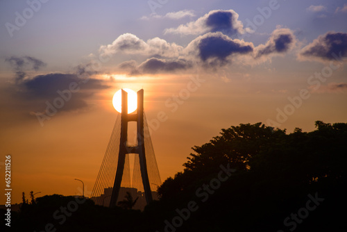 Bridge piers and city silhouette at sunset. The New Taipei Bridge spans the Tamsui River. It is a cable-stayed bridge.