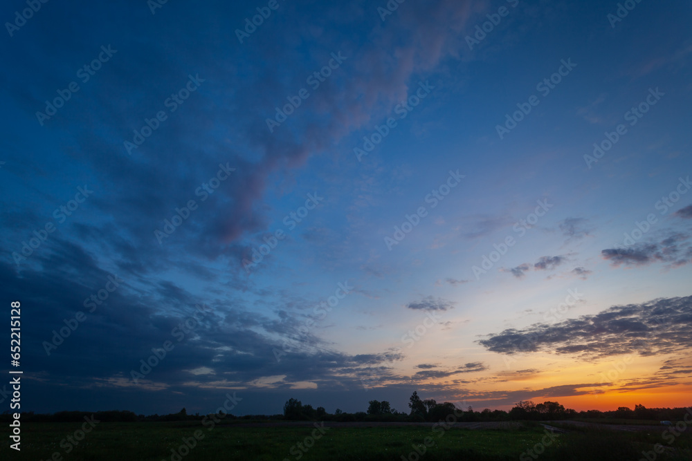 View of evening clouds and sky after sunset over a meadow