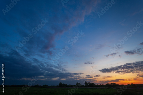 View of evening clouds and sky after sunset over a meadow