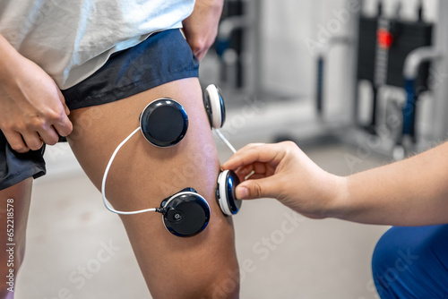 The procedure of myostimulation on the legs of a woman. photo