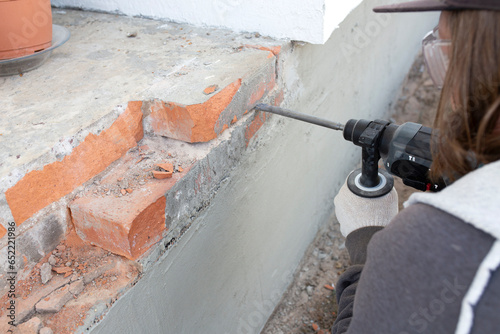 A man breaks a brick from the foundation. Dismantling of destroyed bricks. House restoration.