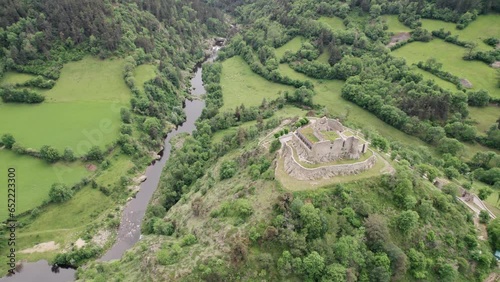 Aerial View of Medieval Castle in Europe Overlooking Lush and Green River Valley photo