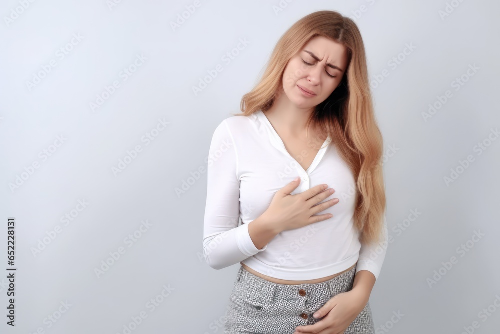 Young woman suffering from heart attack on grey background. Health care concept Young woman suffering from heart attack on grey background. Health care concept
