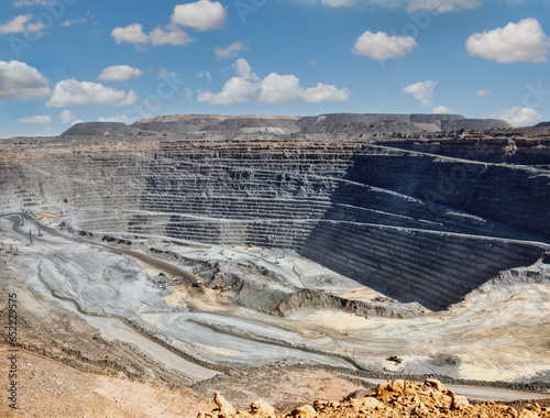 diamond mine open pit, panoramic view of the quarry layers, earth moving machines in the background photo