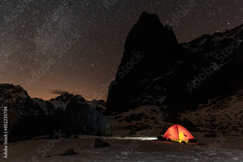 Tent at campground under milky way night landscape in snowy mountains photo