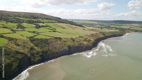 Aerial drone panning shot of North Yorkshire coastline, Ravenscar with green fields and ocean photo