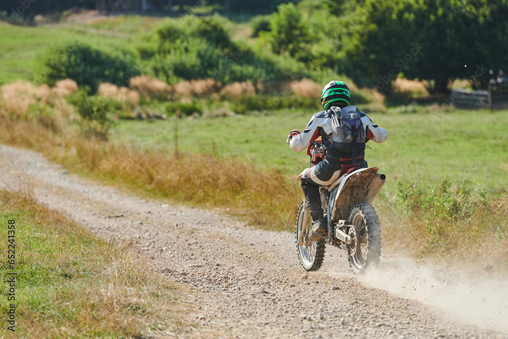 A professional motocross rider exhilaratingly riding a treacherous off-road forest trail on their motorcycle.