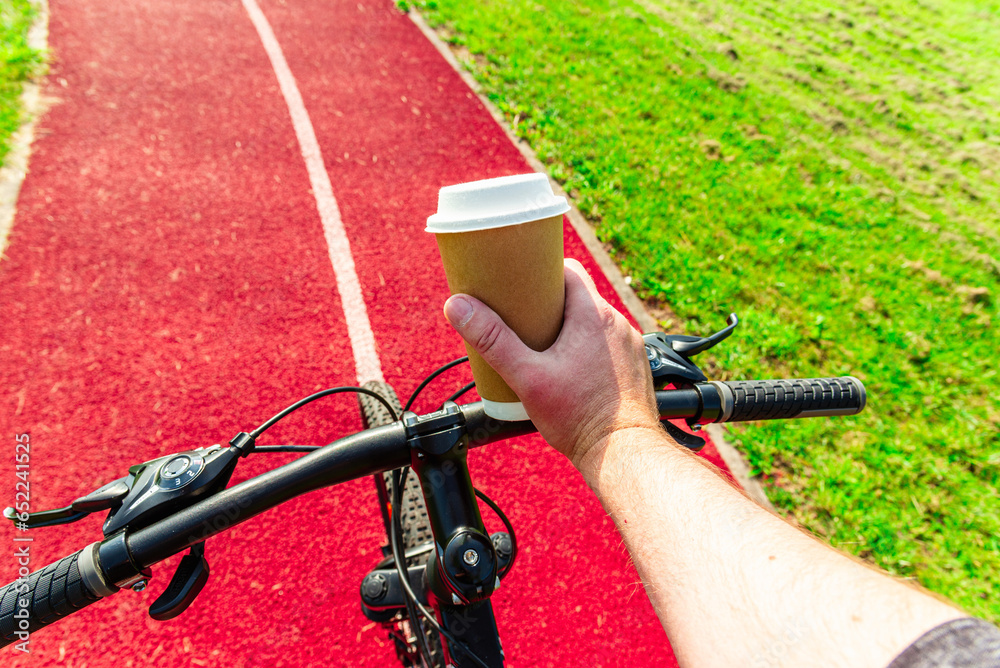 Cup of hot coffee in hands of a bicycle commuter. A minute of respite.Going to work by bike, active sport lifestyle concept.
