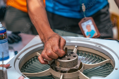 Electrician repairing a broken fan on a table close up