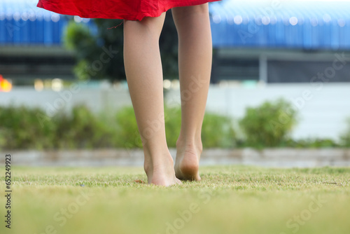 Children's feet are walking barefoot on the green grass. Self-massage on natural surfaces to correct curvature. photo