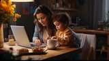 A mother works on a laptop with her son in her arms. Stay at home mom.