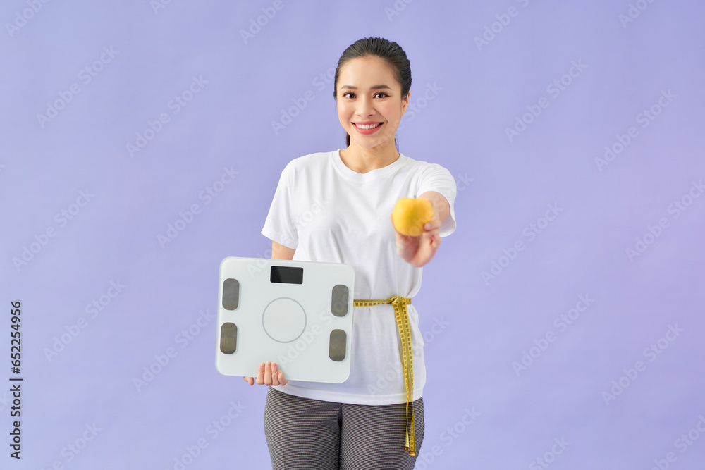 woman measuring waist with tape on knot isolated on violet background, holding yellow apple woman measuring waist with tape on knot isolated on violet background, holding yellow apple