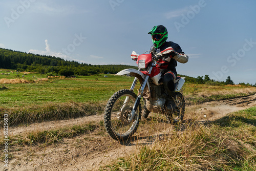 A professional motocross rider exhilaratingly riding a treacherous off-road forest trail on their motorcycle. photo