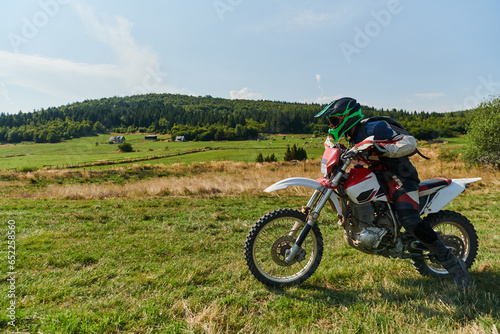 A motorcyclist equipped with professional gear, rides motocross on perilous meadows, training for an upcoming competition.