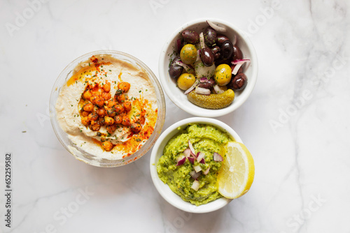 Appetizing hummus and sauces decorated with green on table