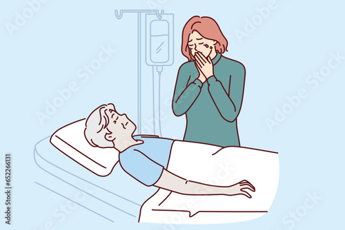 Crying woman stands near hospital bed with terminally sick father in need of expensive operation. Frustrated daughter is stressed by lack of health insurance of sick dad suffering from blood cancer