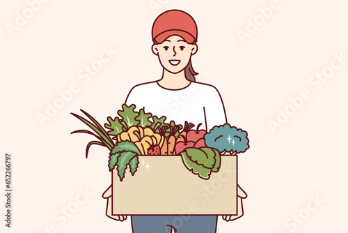 Woman farmer holds box of vegetables and fruits, offering to buy organic food at bargain price. Girl courier delivers eco vegetables grown without use of pesticides and fertilizers