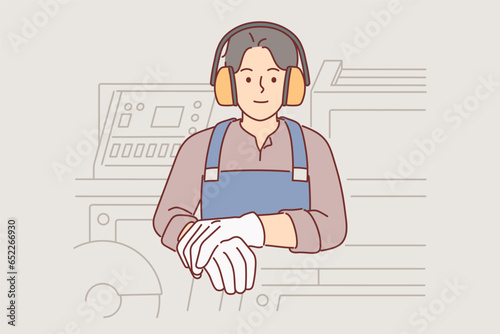 Industrial factory worker man in headphones protecting ears stands near milling machine