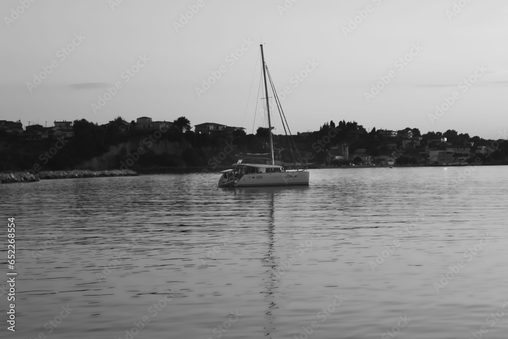Black and white photo of  a small boat in the sea.