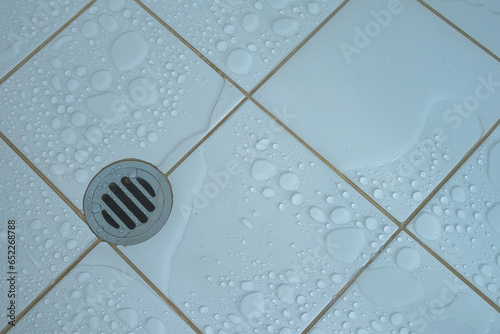Top view of drainage hole stainless and shower water stain with  wet floor on white tile  background.