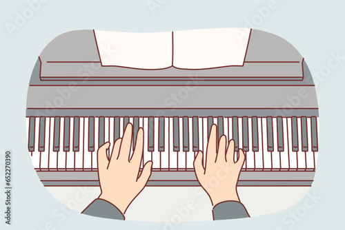 Hands of pianist playing classical composition on piano during symphony concert at opera house
