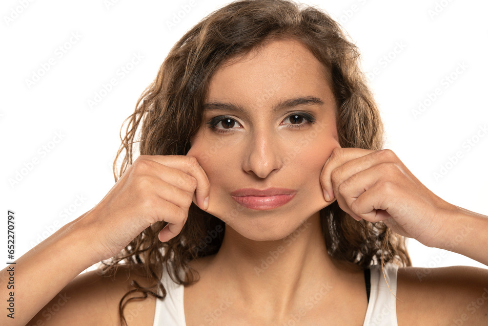 Portrait of young cyrly brunette woman, pulling her cheek skin on white background Portrait of young cyrly brunette woman, pulling her cheek skin on white background