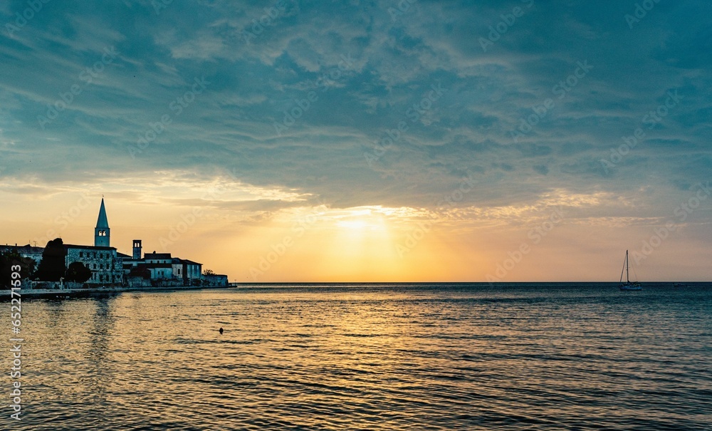 Scenic shot of the calm sea with the evening sunset shining through the clouds in Porec, Croatia
