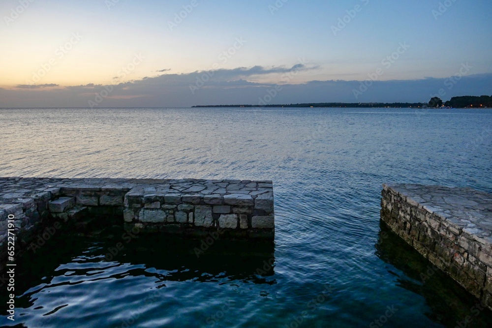 Scenic shot of a brick walkway out to the calm blue sea in Porec, Croatia during the evening