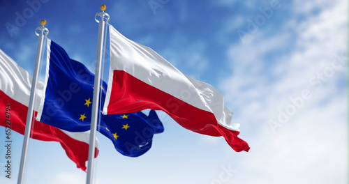 Flags of Poland and the European Union waving in the wind on a clear day