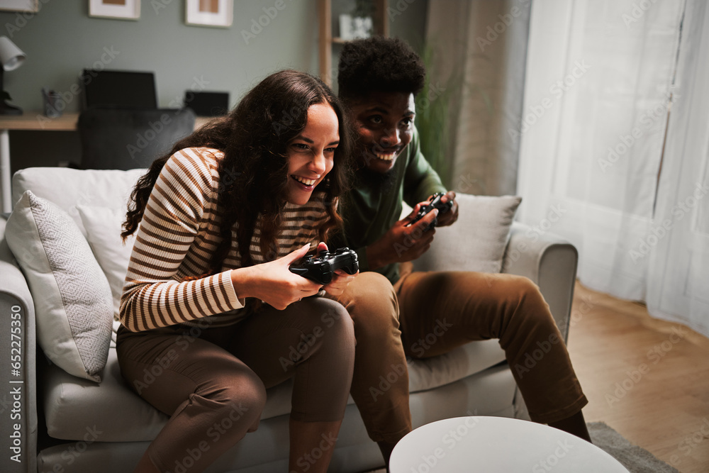 Young cheerful couple playing video games at home