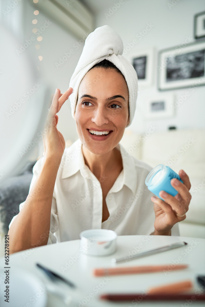 Happy woman applying face cream Happy woman applying face cream