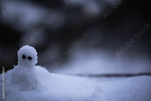 Adorable miniature snowman figurine is situated in a winter wonderland of freshly fallen snow