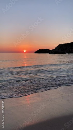 Vertical landscape scene of Cala salada beach with orange sunset horizon sly in Ibiza, Spain photo