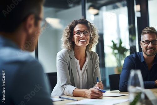 business, people and teamwork concept - smiling businesswoman with eyeglasses talking in office