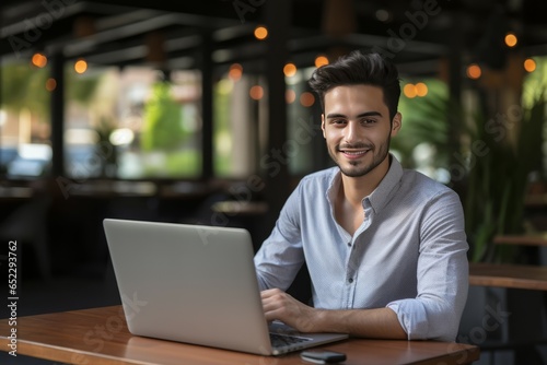 Portrait of smiling african american man using laptop in cafe, looking at camera.